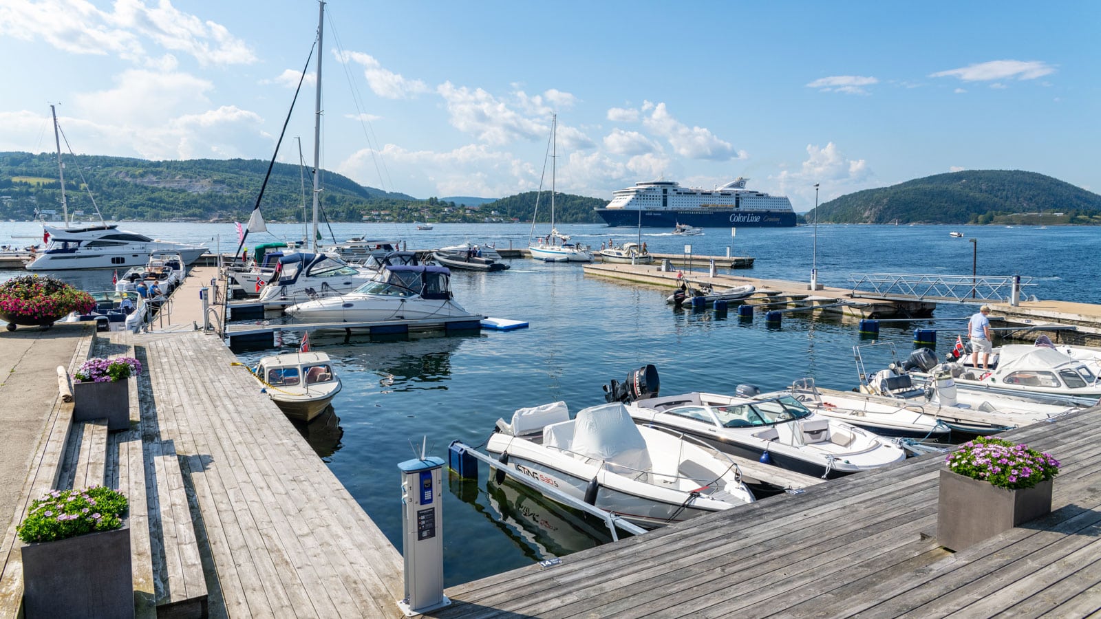 Båter i en gjestehavn med en større cruisebåt som seiler forbi i Oslofjorden