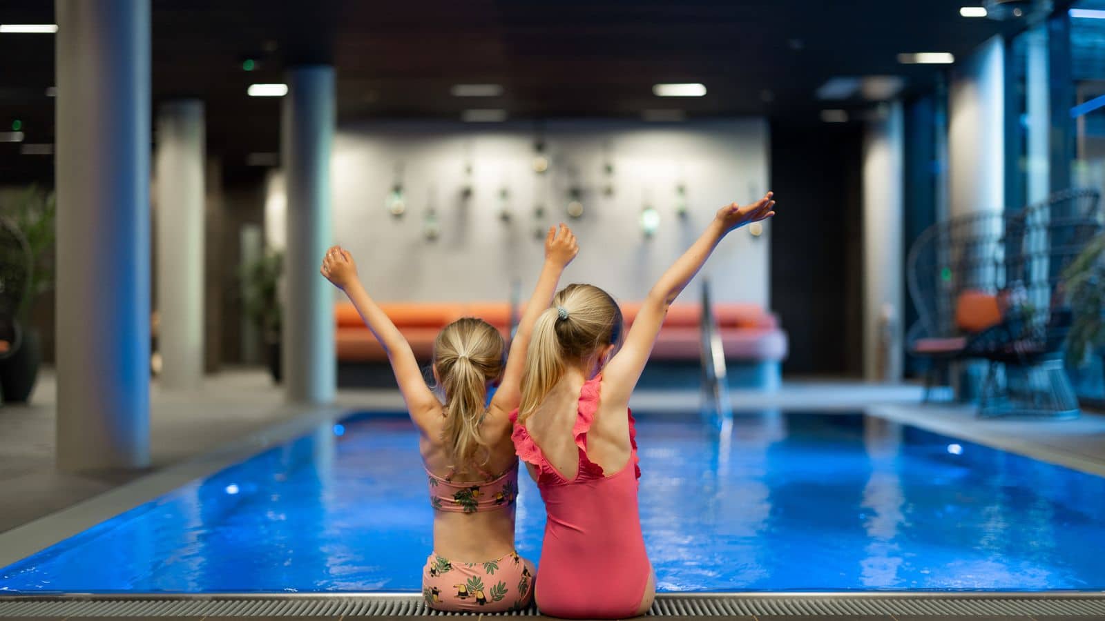 2 jenter sittende ved et basseng sett bakfra