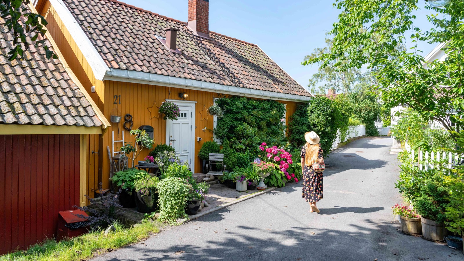 Jente som går i Badehusgata med blomsterforbi et oransje hus