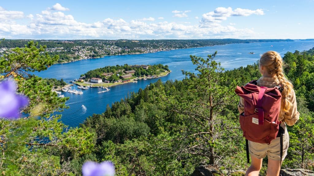 dame med sekk på en topp som ser ut over Oslofjorden og Oscarborg
