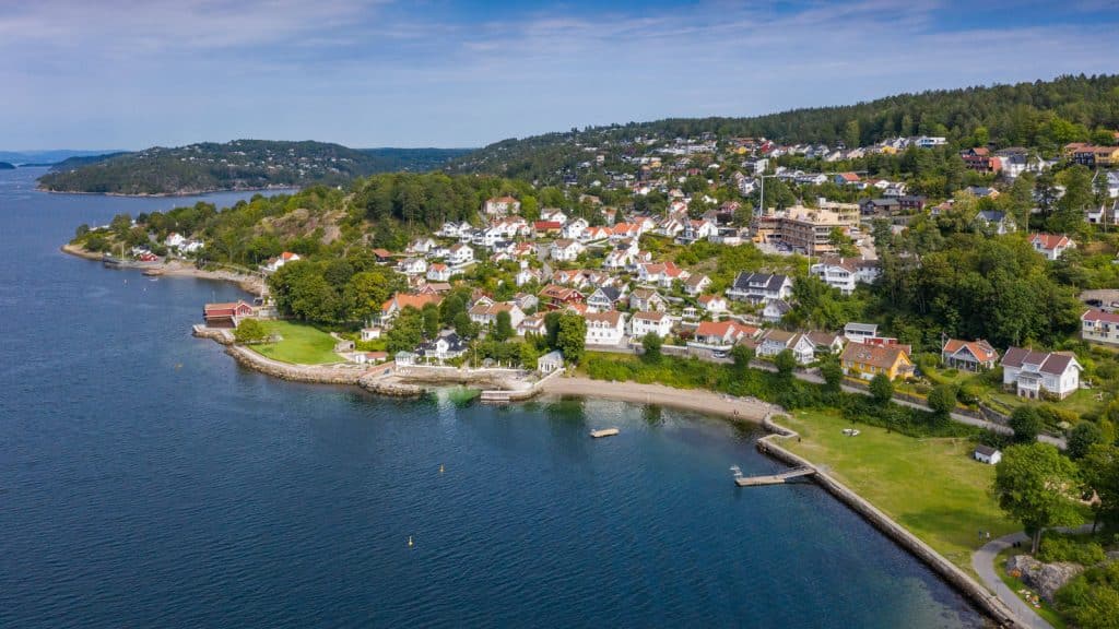 Gressslette og strand med hvite trehus