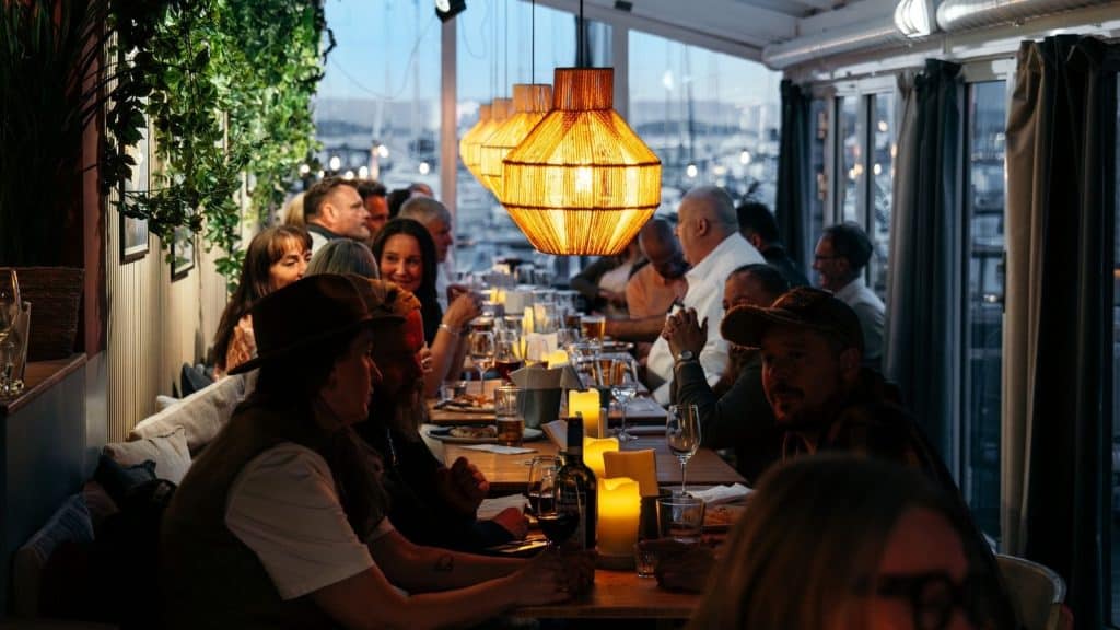 Folk som sitter inne rundt et langbord dempet belysning