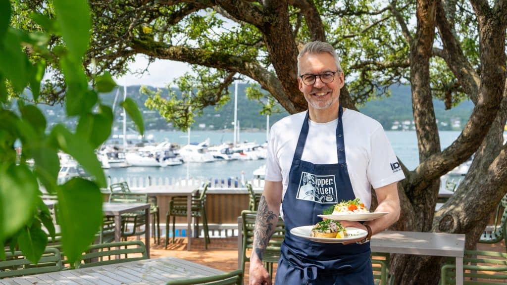 Mann som holder matrett på uteservering av restaurant