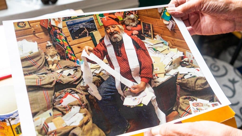 Mann som sitter utkledd som nisse med julepost