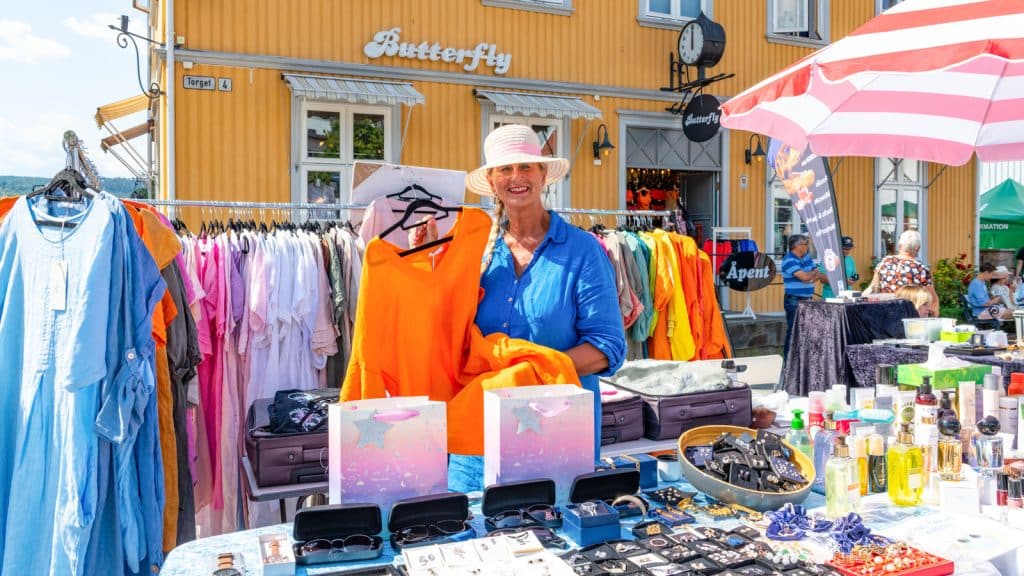 Dame som står med en oransje tunika på et torg