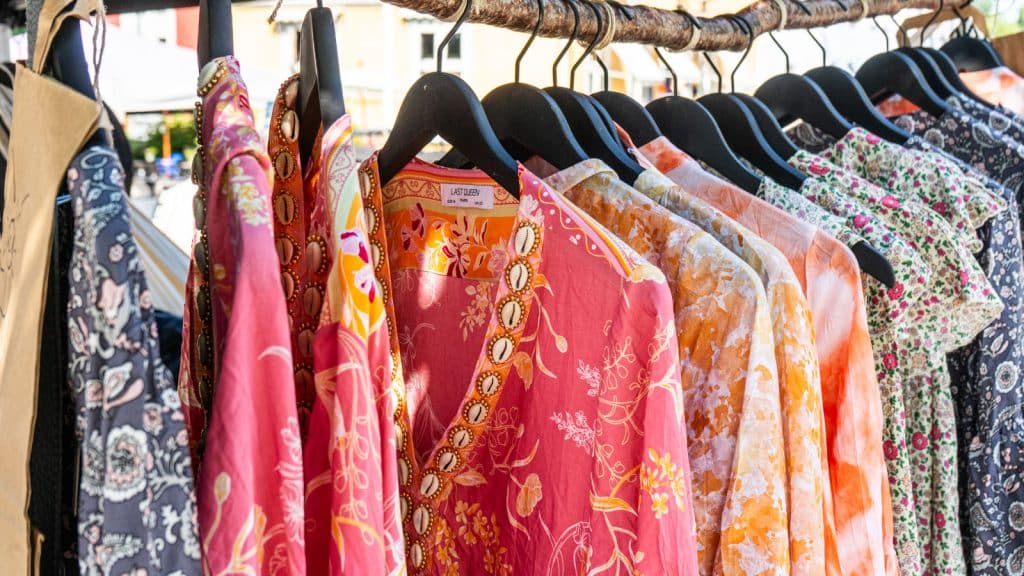 Colourful tunics for sale on a wooden clothes rack