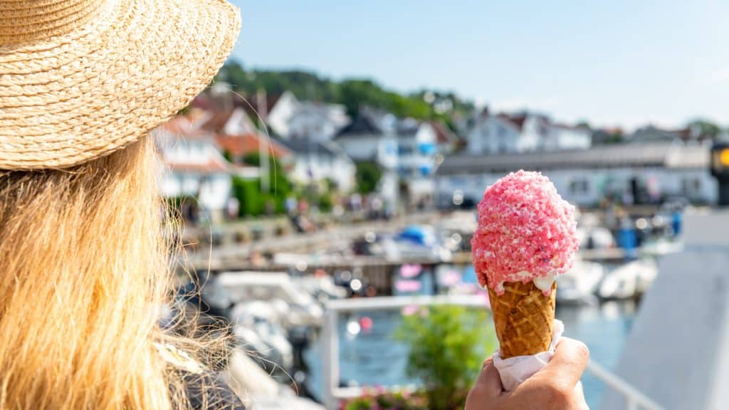 Dame som spiser is i en havn om sommeren