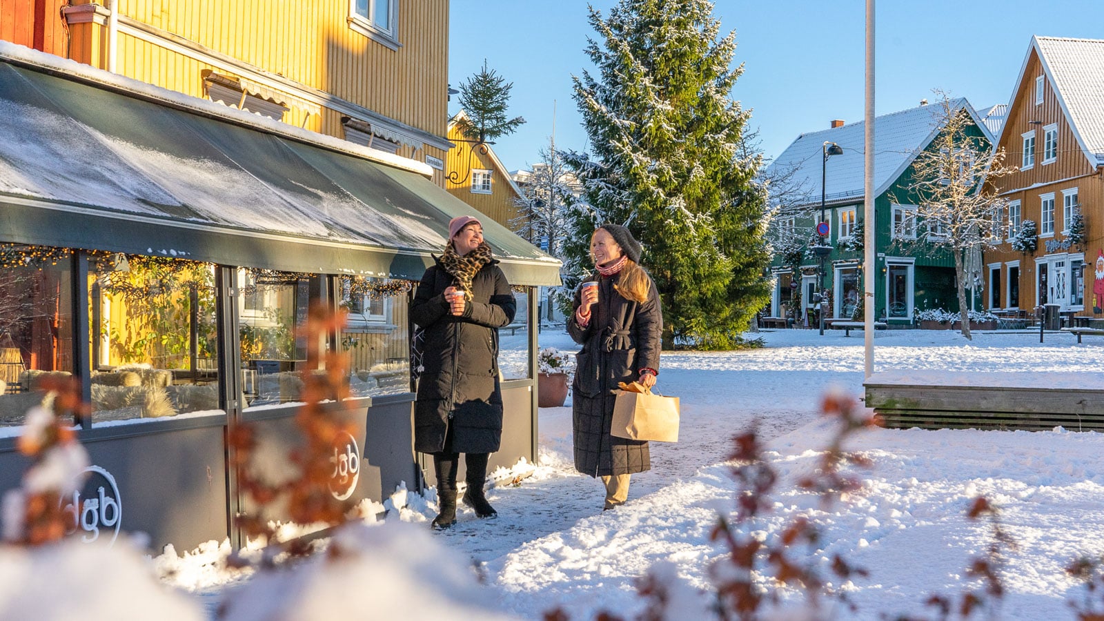 To damer som shopper i Drøbak utenfor en kafe og det er snø på bakken