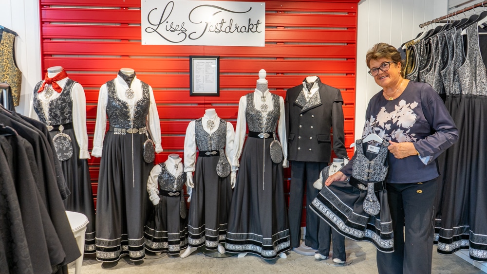 Lady holding a party suit in a shop with other party suits