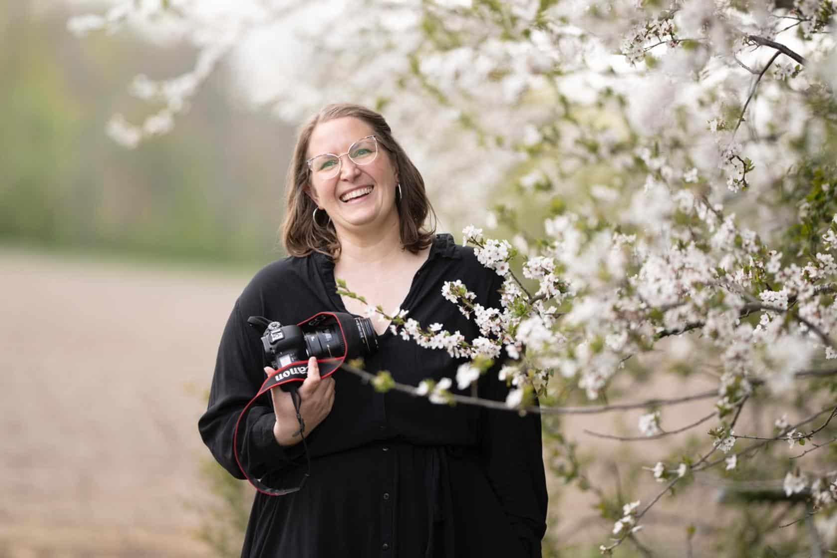 Bilde av dame som holder et kamera med kirsebærblomster rundt seg