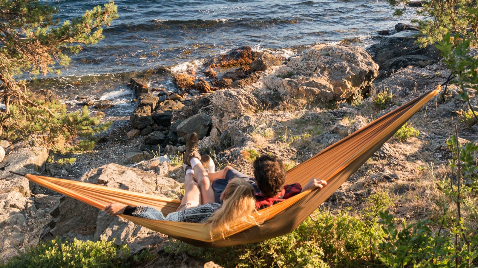 Et par som ligger i hengekøya ved fjorden