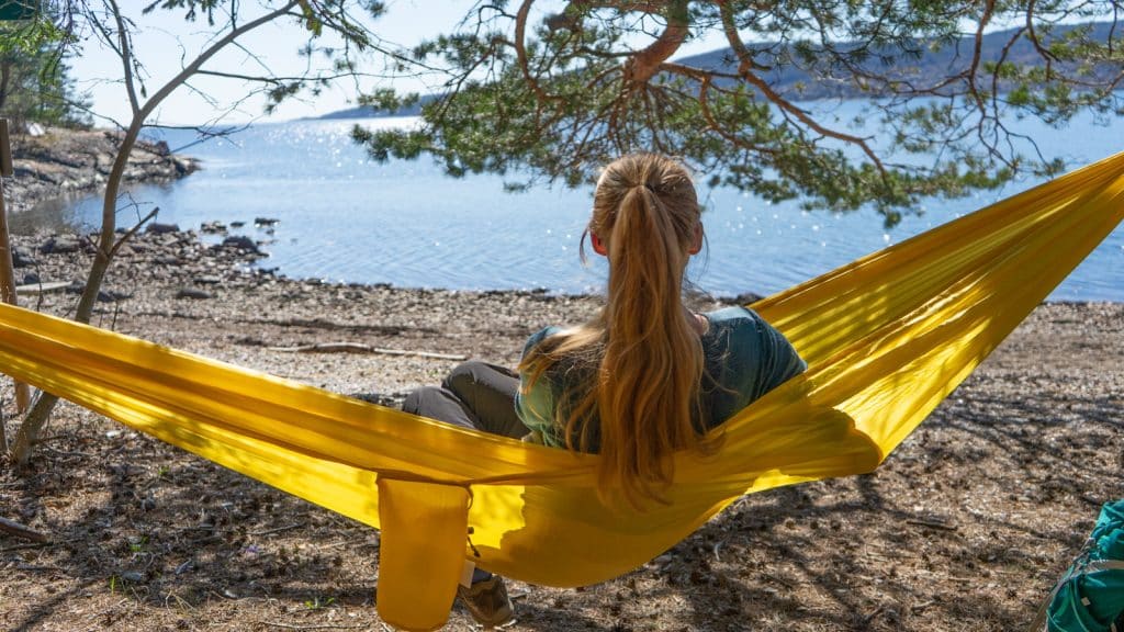 Dame i gul hengekøye på strand