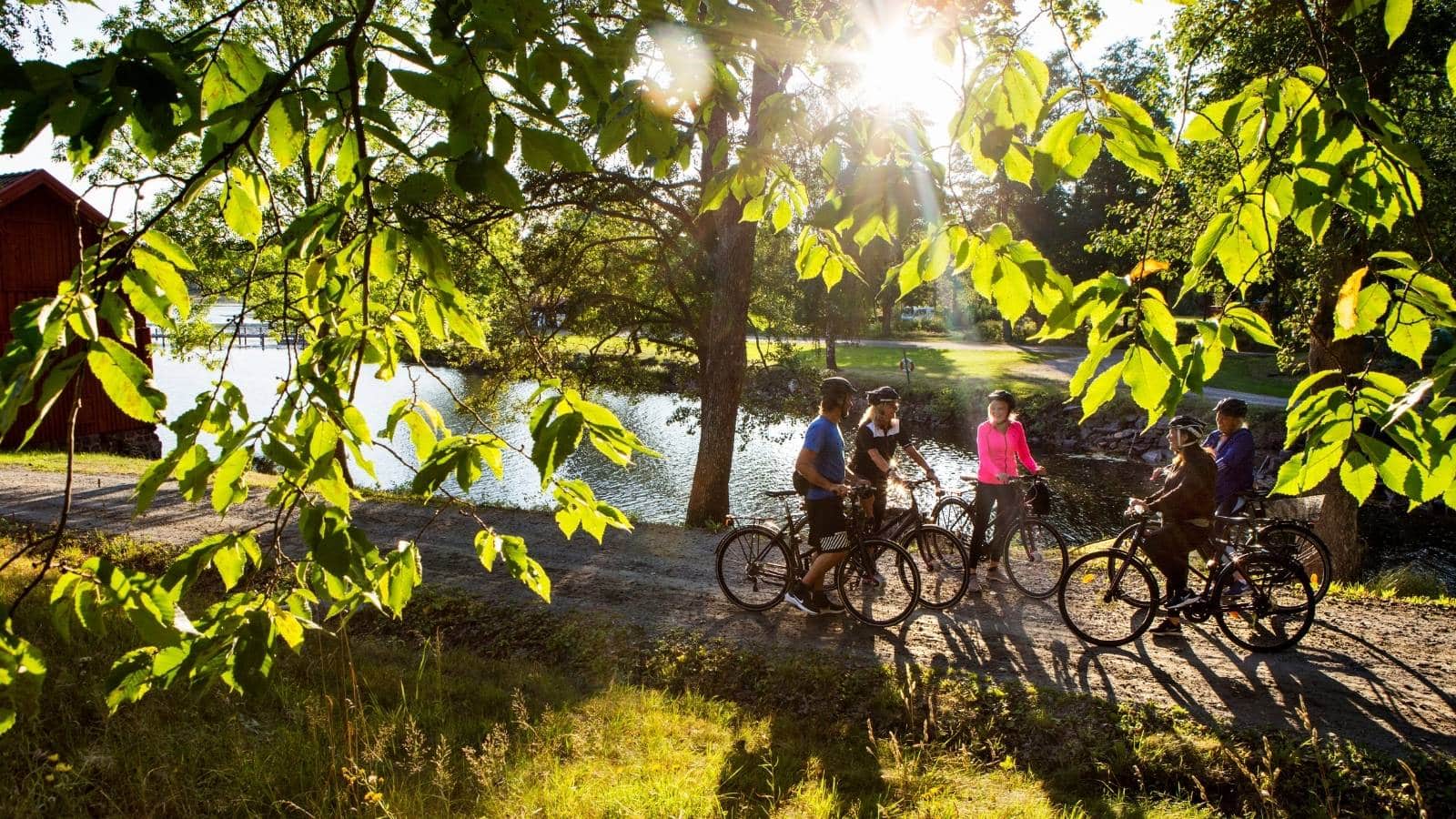 5 personer står og hvilker med sykler ved en sjø
