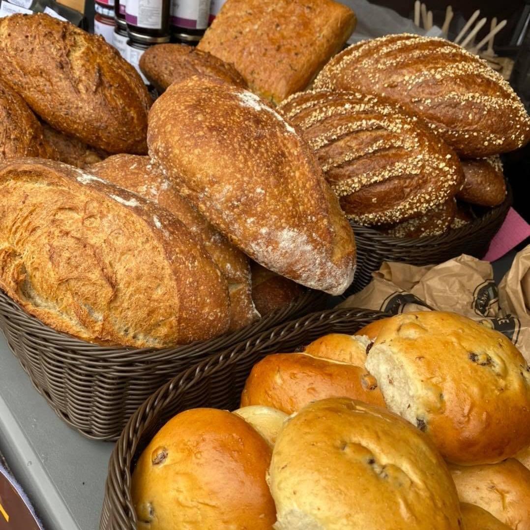 mange brød i en kurv og boller ved siden av